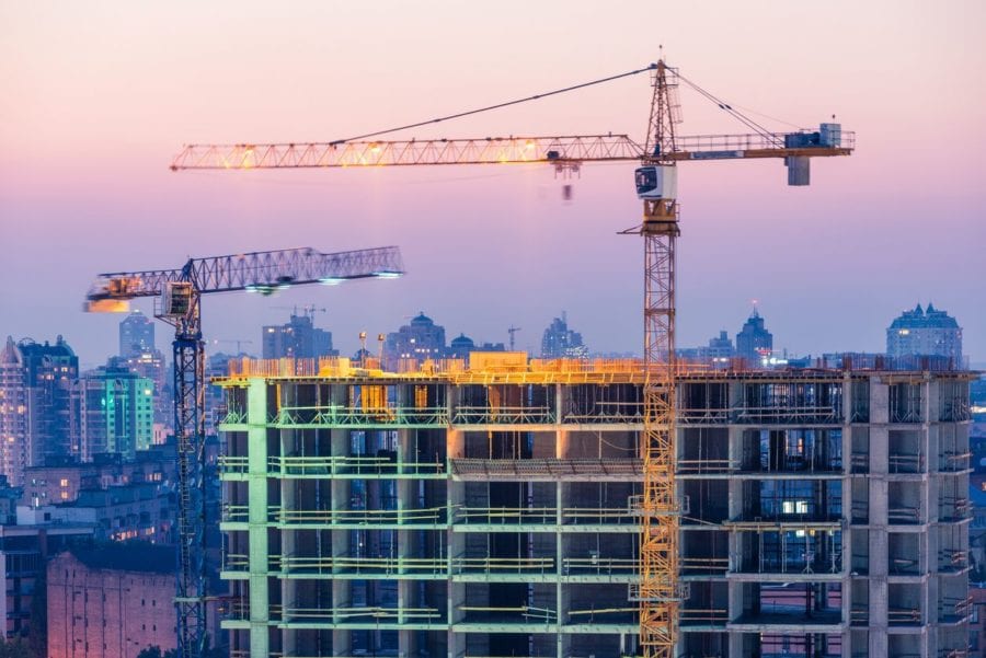 A building under construction with cranes in the background.